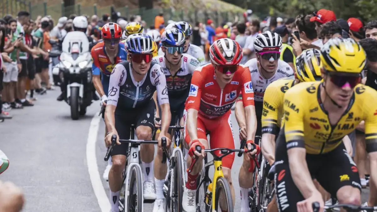 Cyklistpeloton under Vuelta a España med röda ledartröjor på en solig bergsetapp i Spanien